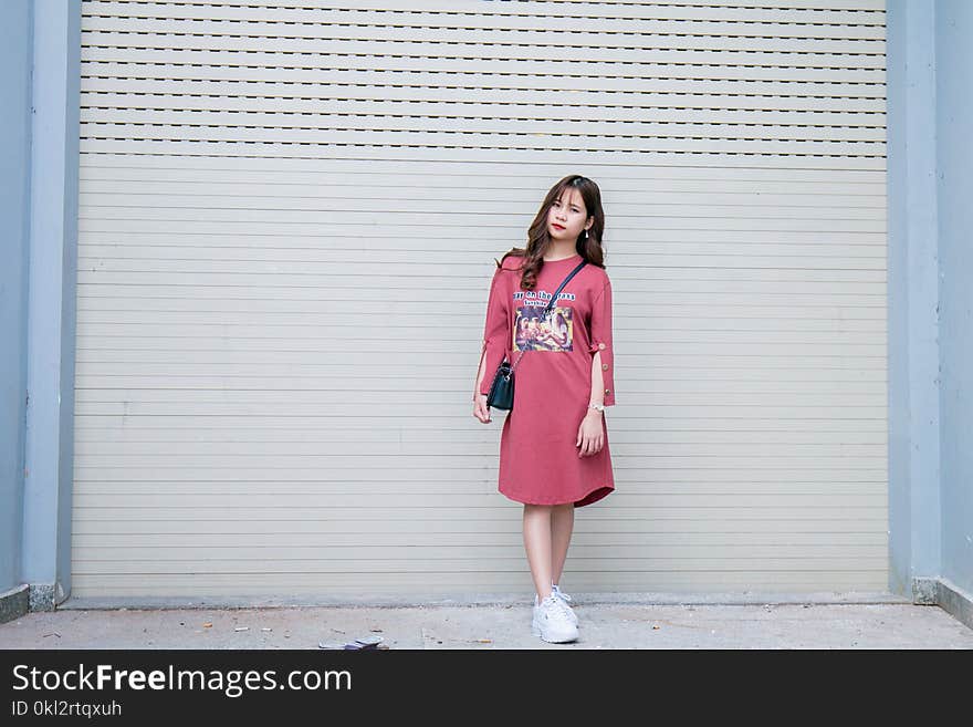 Woman Wearing Pink Long-sleeved Dress Standing Behind the Wall