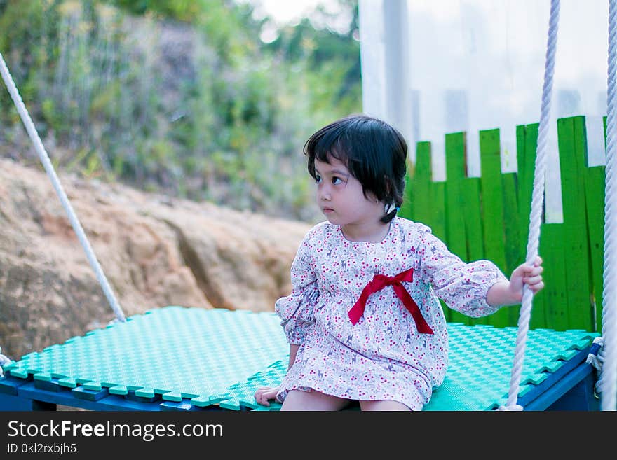 Girl Wearing White Long-sleeved Dress While Sitting on Swing