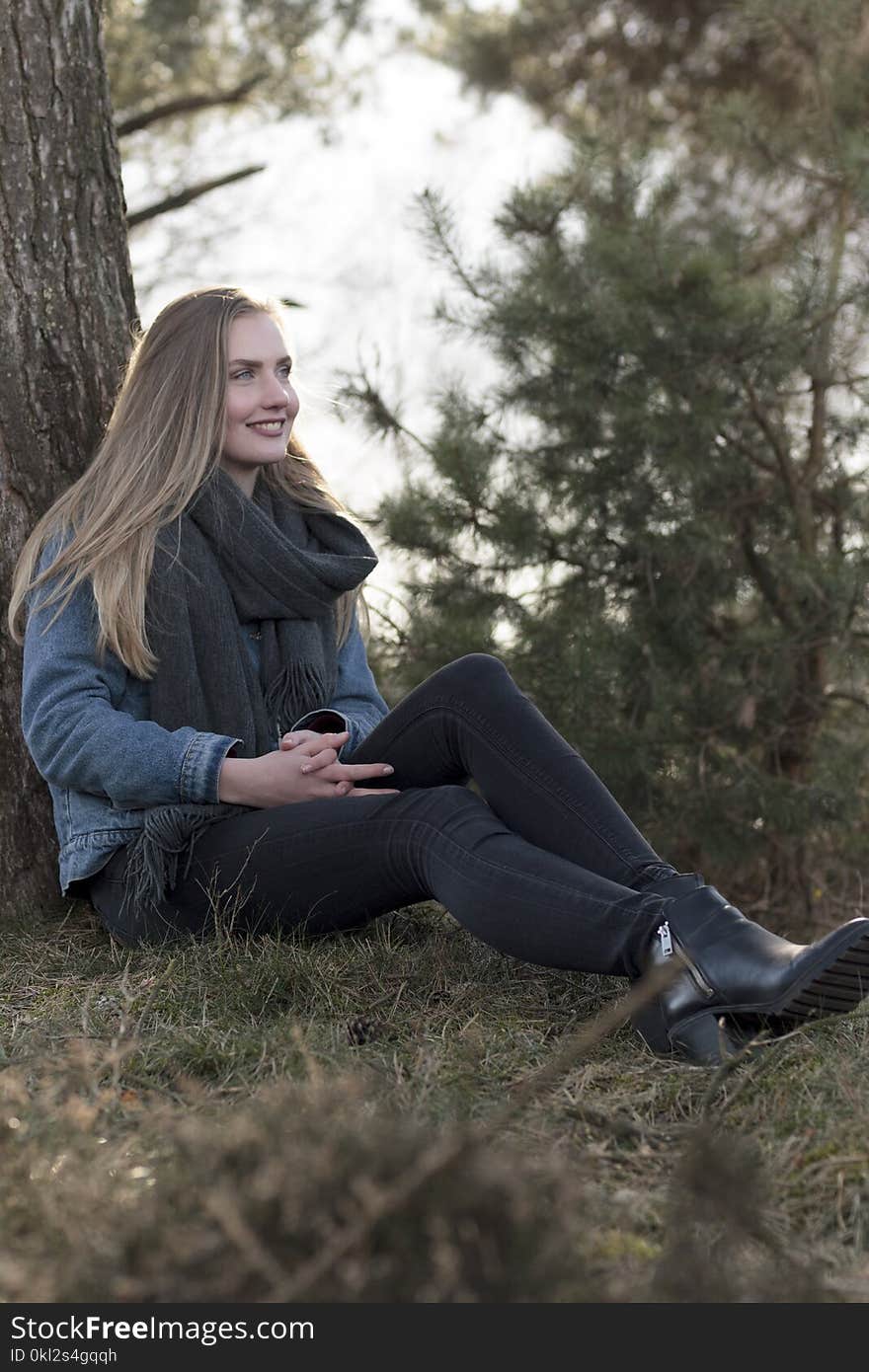 Woman Sitting on Ground Leaning Against Tree