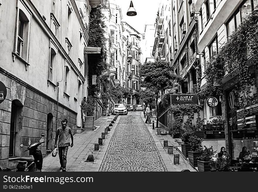 Grayscale Photography of Man Walking Down Road Near Mountain