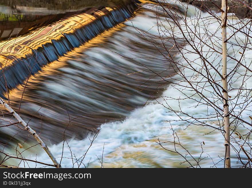 A bubbling river with a rapid and reflection and two young silver birches in early spring