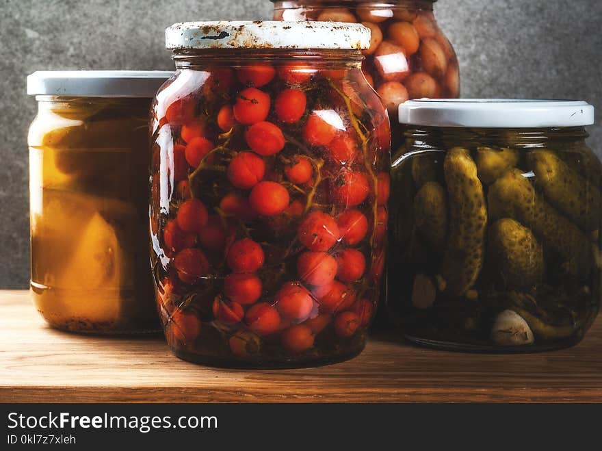 Homemade preserving, canning food, pickled or fermented vegetables in glass jars over kitchen drawer, grey stone wall background, copy space