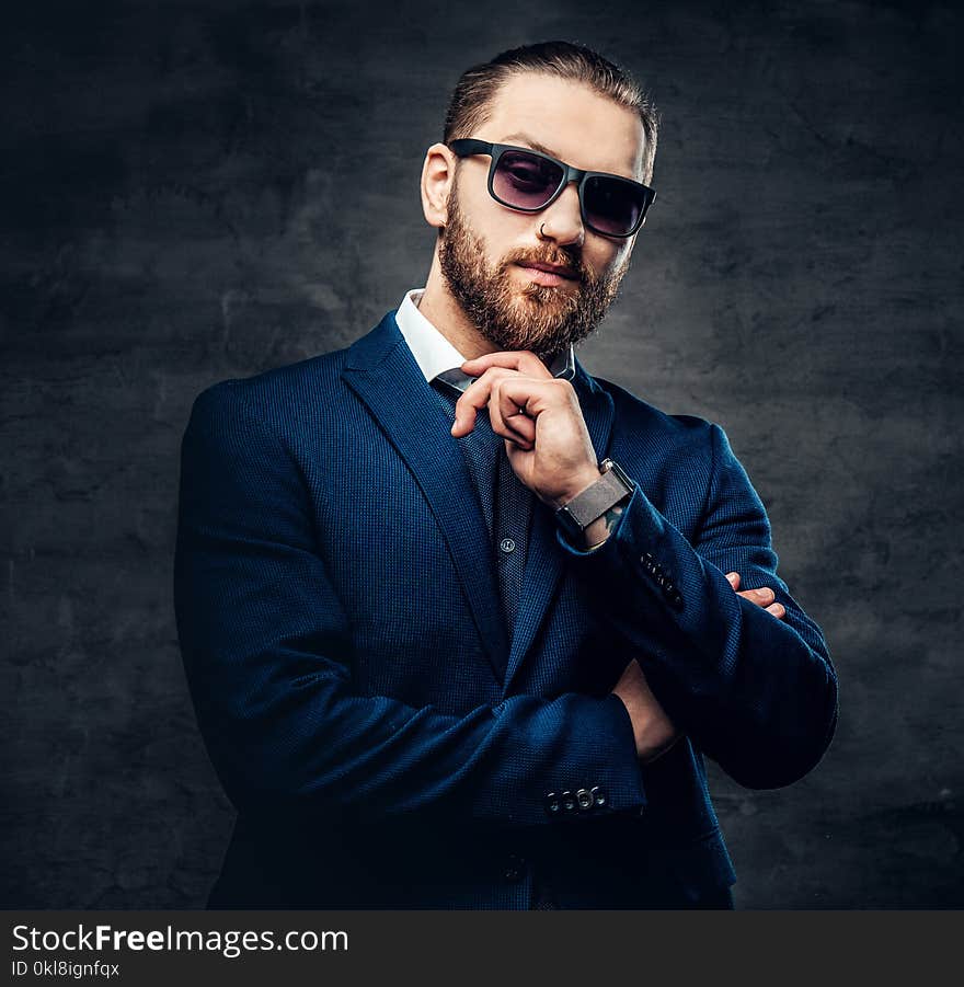 Studio portrait of bearded male in sunglasses and piercing in a nose.