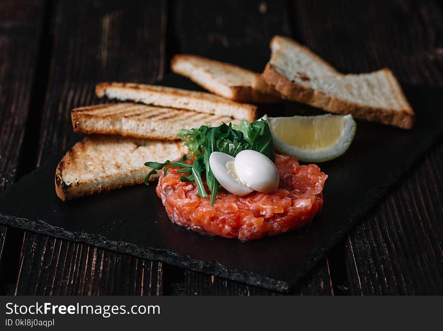 Close-up of salmon tartare served with quail egg, butter, bread