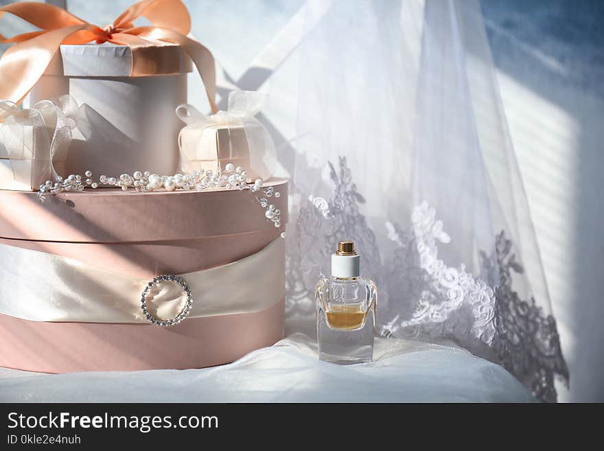 Gift boxes, perfume and bridal veil on white chair