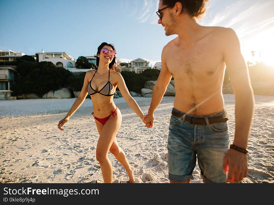 Happy couple in love on beach summer vacation. Joyful men and women walking along the beach holding hands.