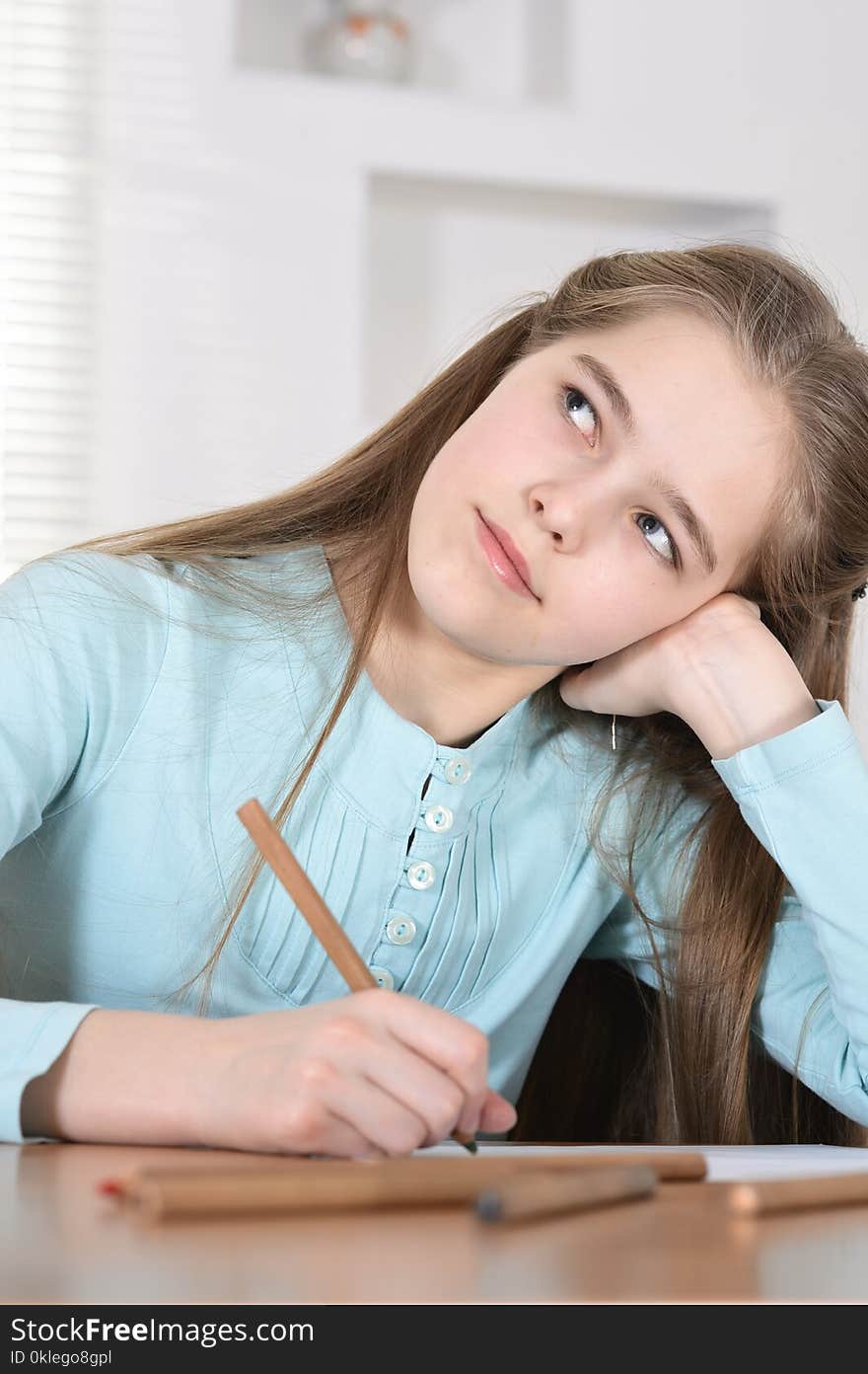 Cute schoolgirl sitting at table and drawing. Cute schoolgirl sitting at table and drawing