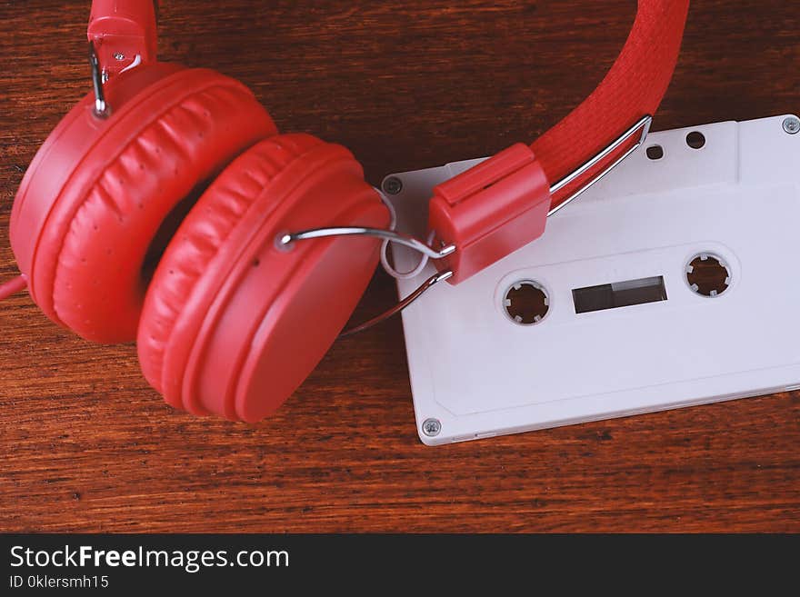 Top view of vintage headphones and audio cassette on wooden table. Retro technology concept