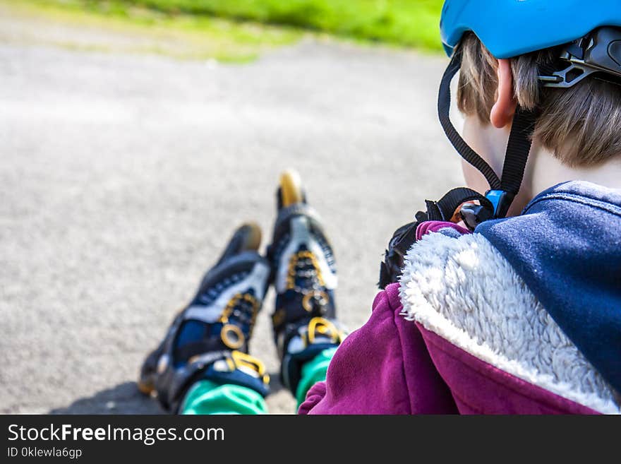 Little boy wearing roller-blades sitting and eating and drinking mineral water