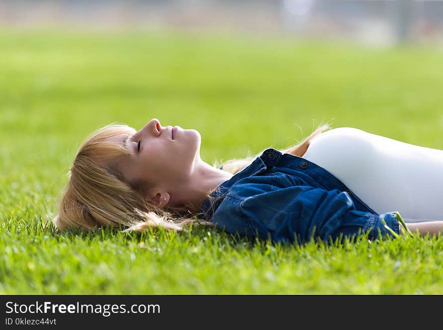 Shot of pretty young woman relaxing while lying on the grass in the park.