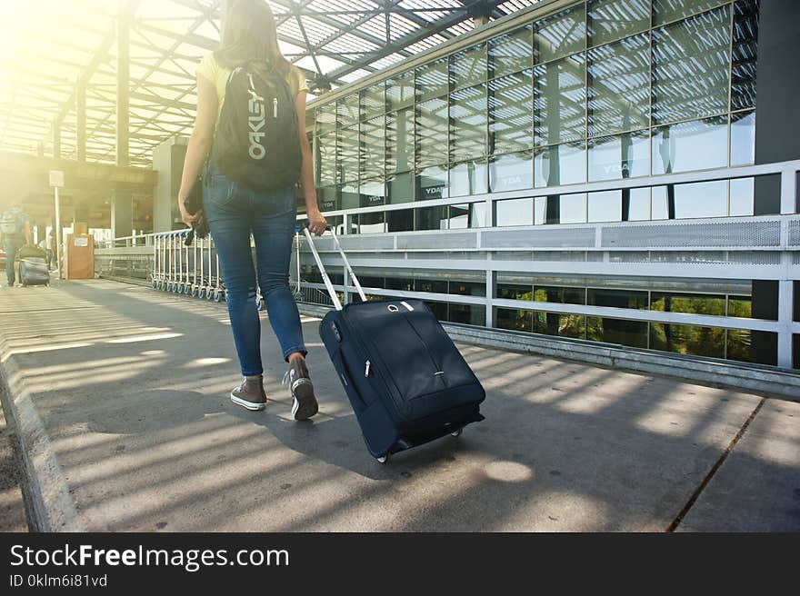 Woman Walking on Pathway While Strolling Luggage