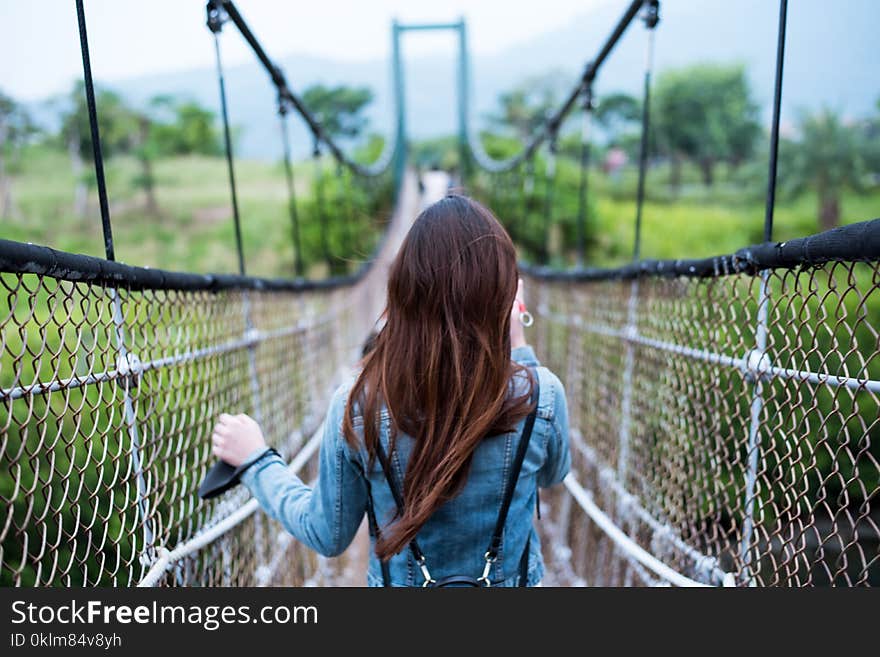 Woman in Blue Long-sleeved Dress on Rope Bridge