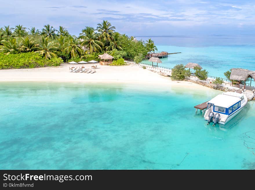 Beige Beach With Huts and Loungers Beside Teal Calm Body of Ocean at Daytime