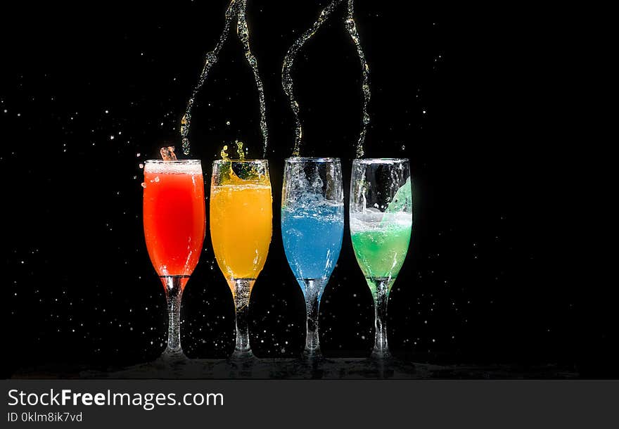 Four Champagne Flutes With Assorted-color Liquids