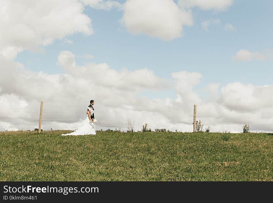 Couple in Wedding Suit and Dress on an Open Fiele