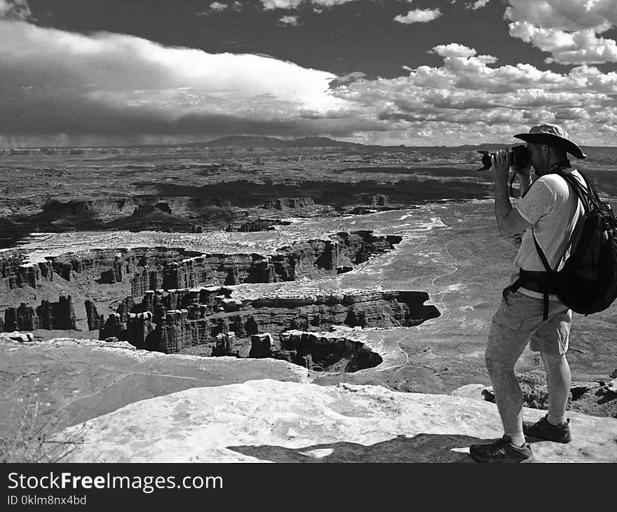 Grayscale Photo of Man Taking Photo of Canyons