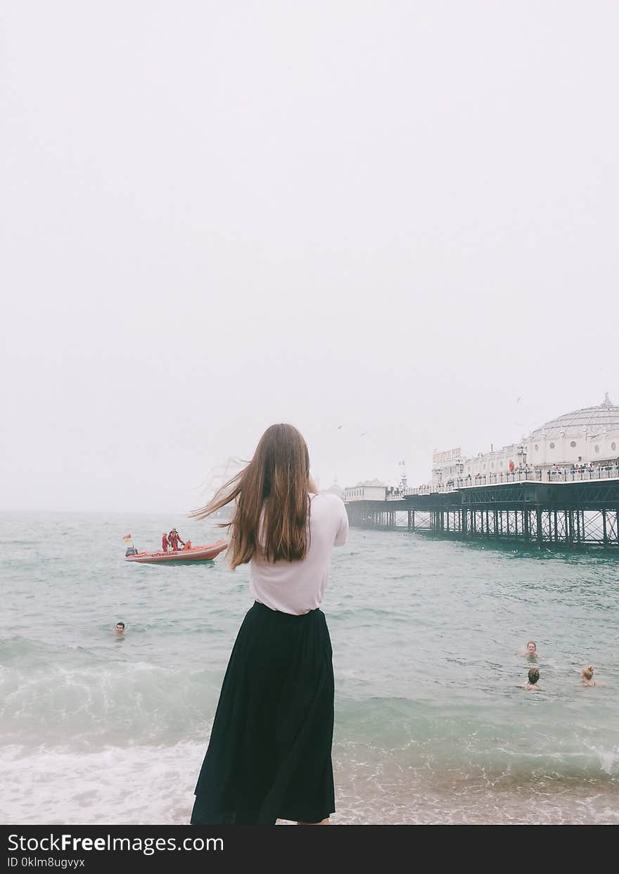 Woman Wearing White Shirt and Black Skirt Standing on Seashore