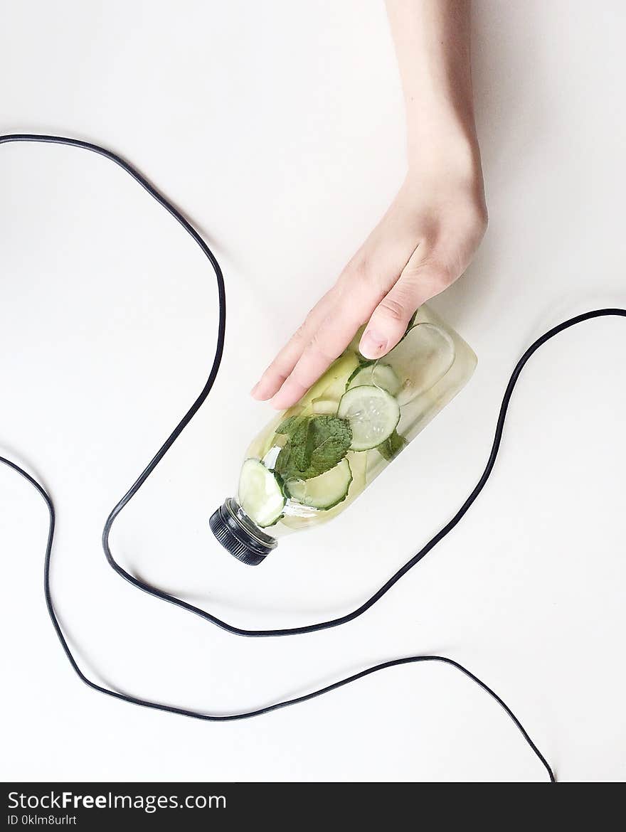 Person Holding Bottle and Cucumber