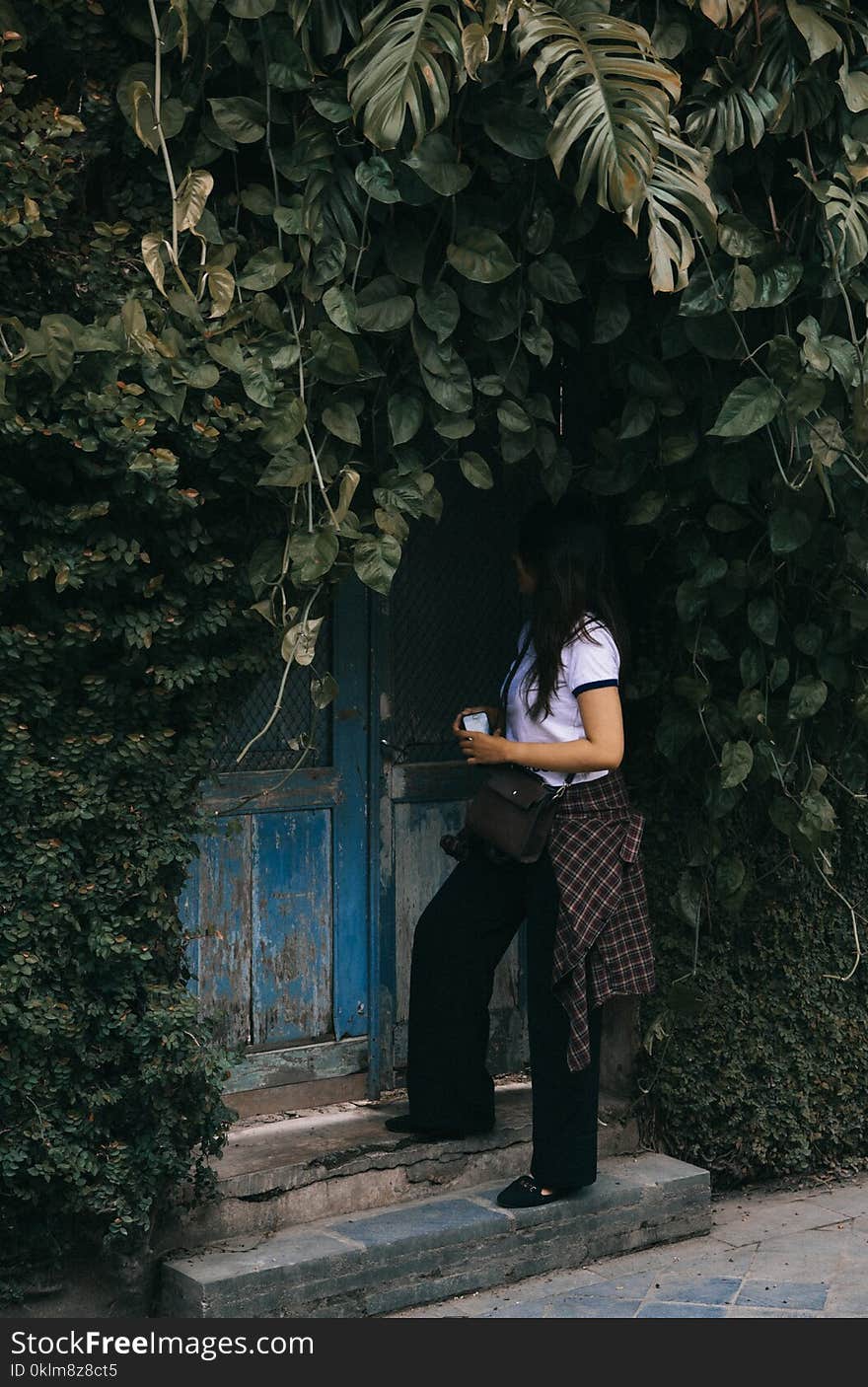 Woman Standing Beside Blue Wooden Door