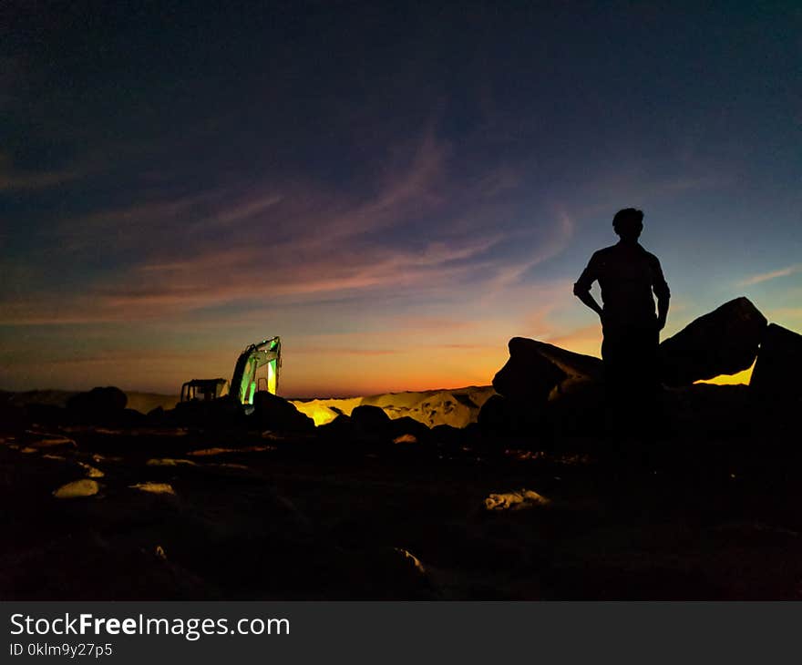 Silhouette Photo of Person Standing Near the Rock