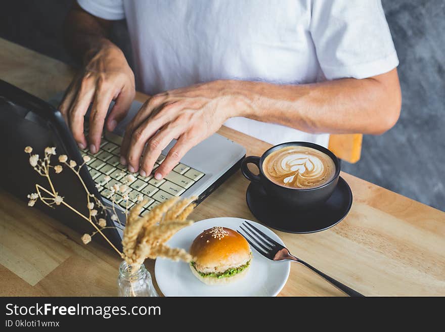 A hand of man pressing computer on table with coffee and bread in coffee shop. A hand of man pressing computer on table with coffee and bread in coffee shop