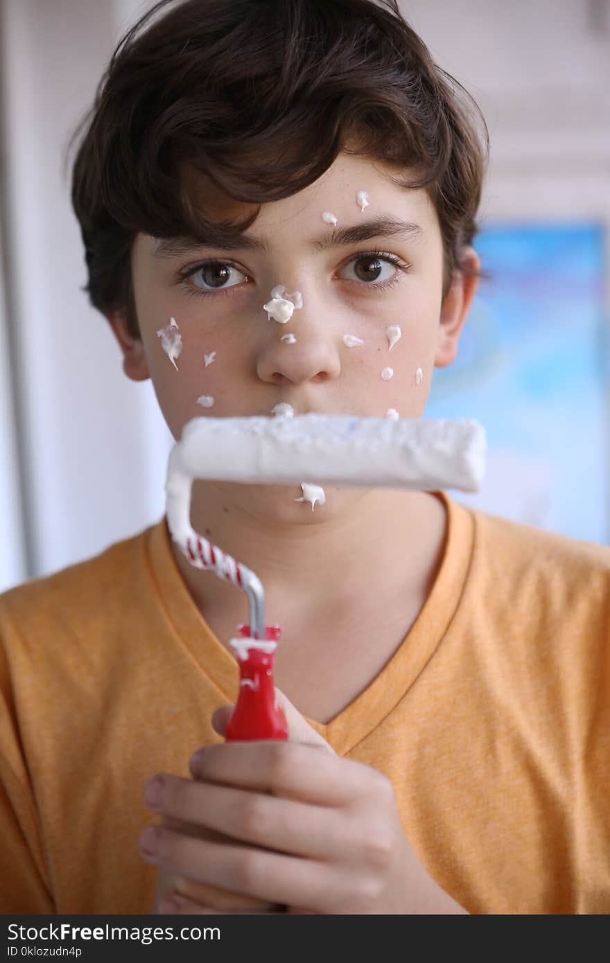 Smiling teenager boy with white paint roller and dirty face make repaint