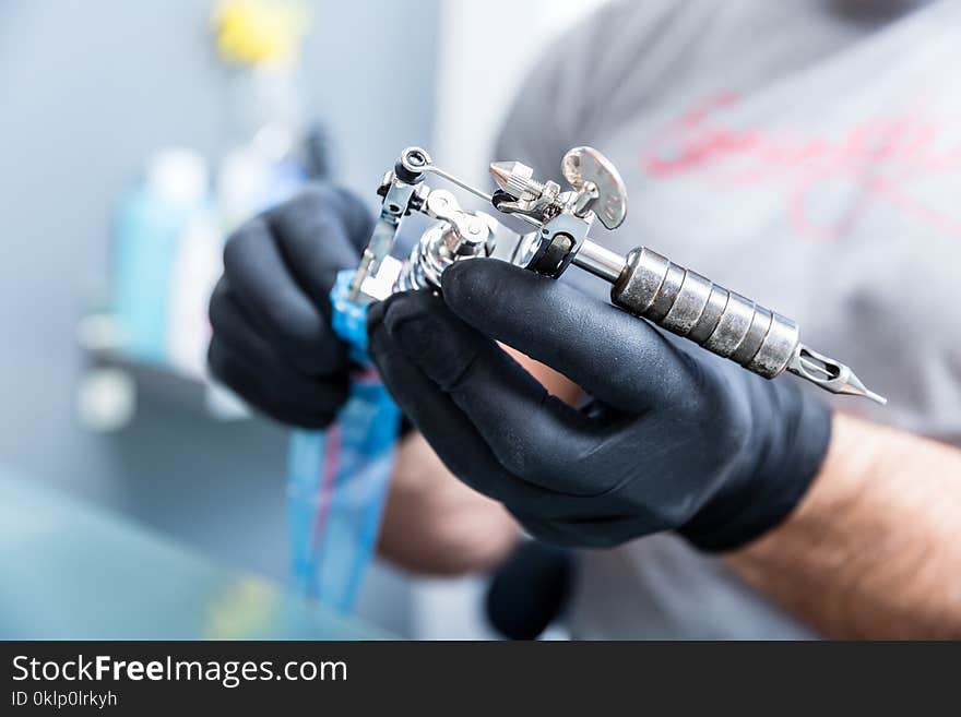 Close-up of the hands of a skilled tattoo artist wearing black gloves