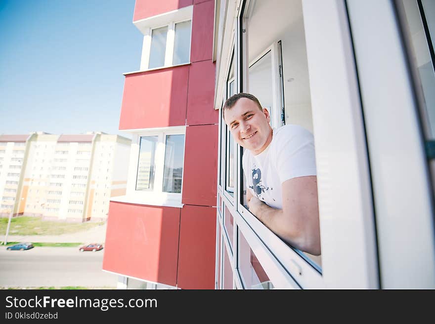 The cheerful guy standing on a balcony.