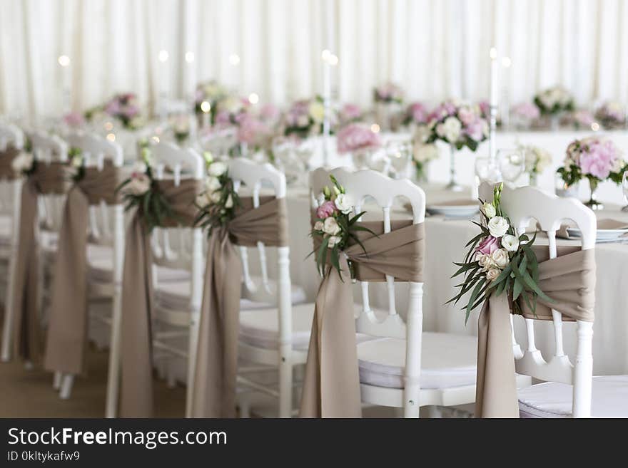 White chairs and tables decorated with flowers and fabric on the wedding day. White chairs and tables decorated with flowers and fabric on the wedding day