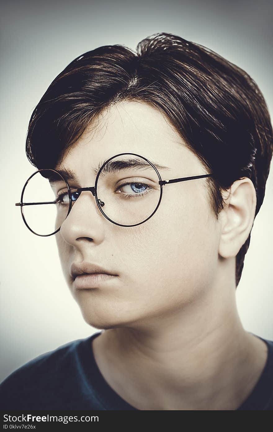 Portrait of a boy wearing eyeglasses blue eyes close, macro studio shot.