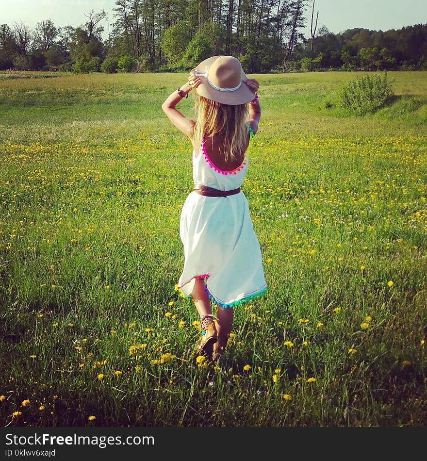 Girl is walking on a green field.