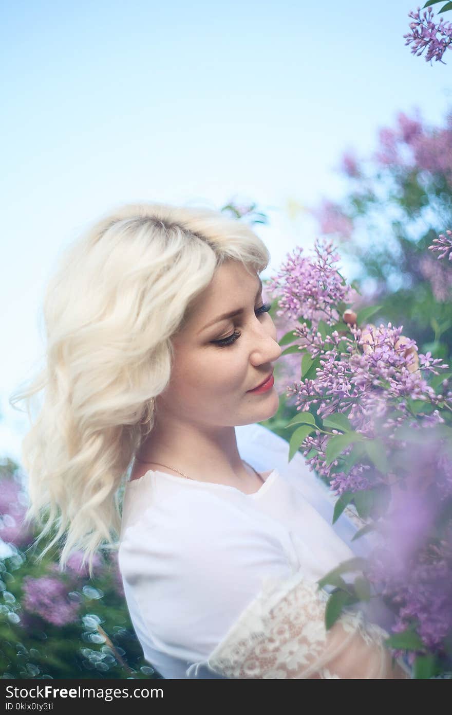 Beautiful woman in a spring garden with blooming lilacs.