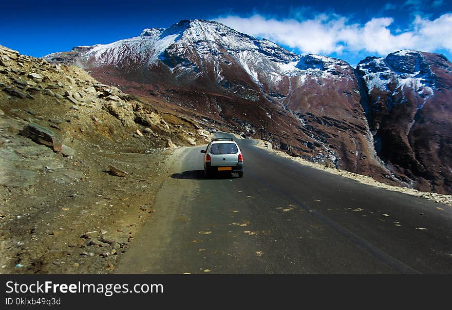 Car driving in hilly highway with green pasture and blue sky on