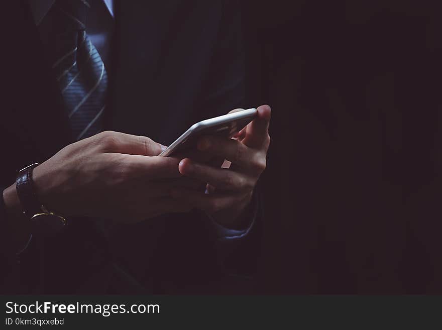 Businessman hand using smartphone in black background