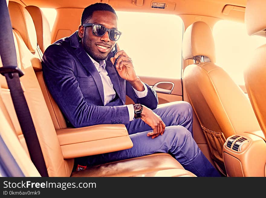 Portrait of black American elegant male talks on smartphone in a car. Filtered warm toned image. Portrait of black American elegant male talks on smartphone in a car. Filtered warm toned image.