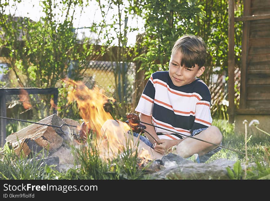 Children enjoy campfire. Boy toasting sausages on the garden. Children enjoy campfire. Boy toasting sausages on the garden.