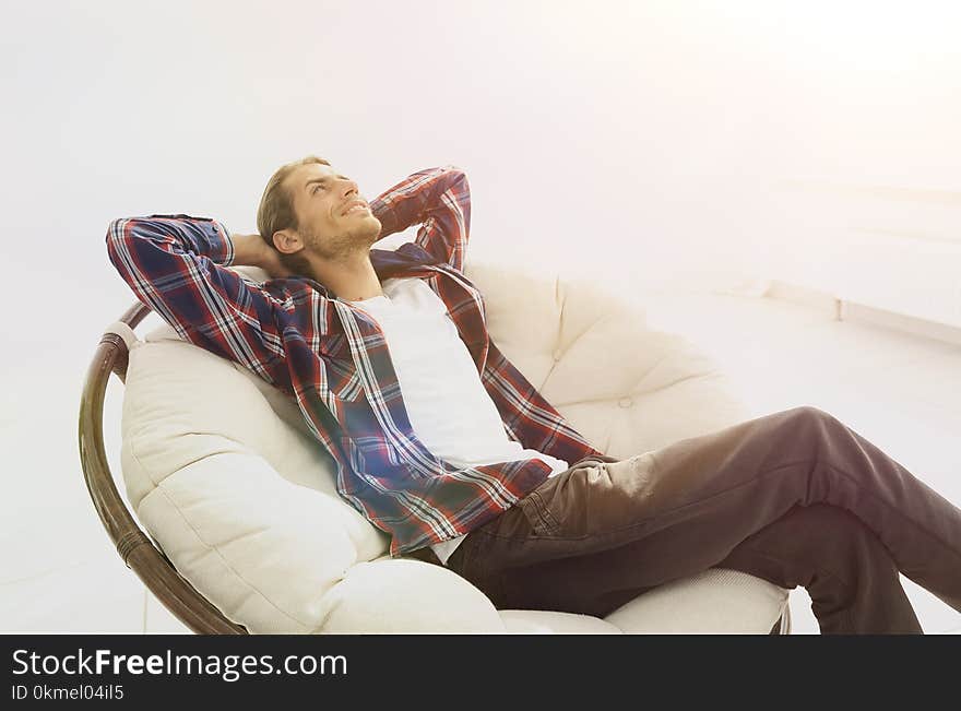 Serious guy rests sitting and dreaming in a large comfortable chair.