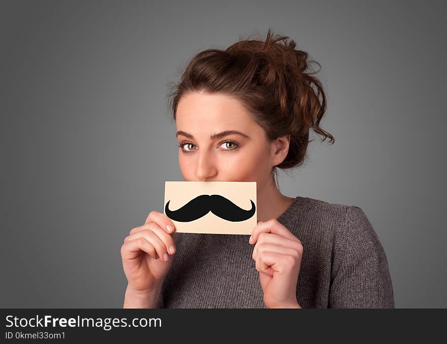 Happy cute girl holding paper with mustache drawing on gradient background