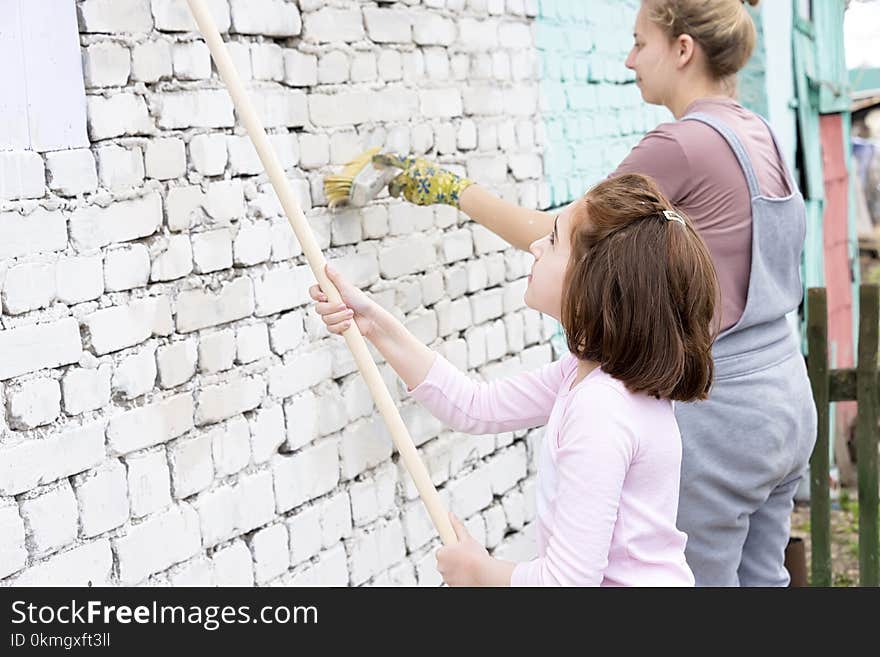 Girls kids paint the walls with roller and paint in green face paint, mom and daughter work. Girls kids paint the walls with roller and paint in green face paint, mom and daughter work