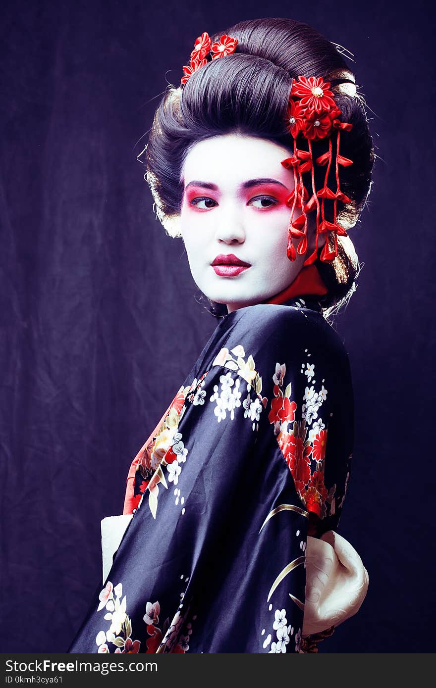 Young pretty geisha in kimono with sakura and decoration on black background