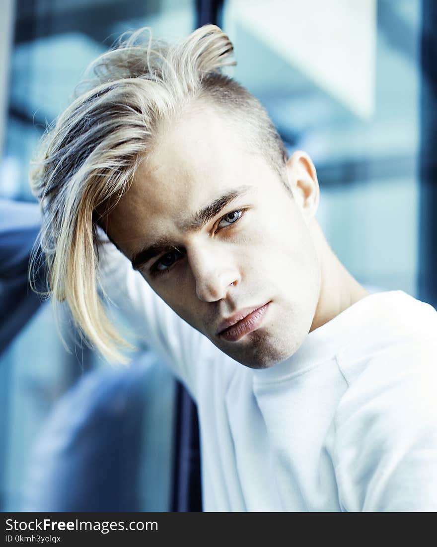 Young modern hipster guy at new building university blond fashion hairstyle having fun, lifestyle people concept close up