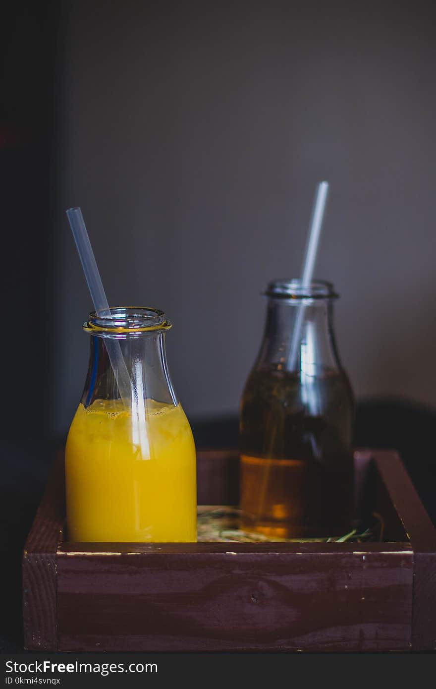 Two Clear Glass Bottles on Brown Wooden Crate