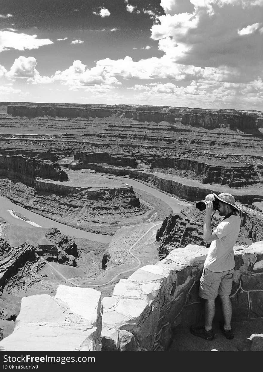 Man Standing Holding Camera Near Grand Canyon Grayscale Photo