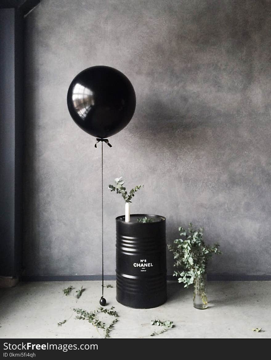 Grayscale Photography of Balloon Beside Chanel Metal Barrel