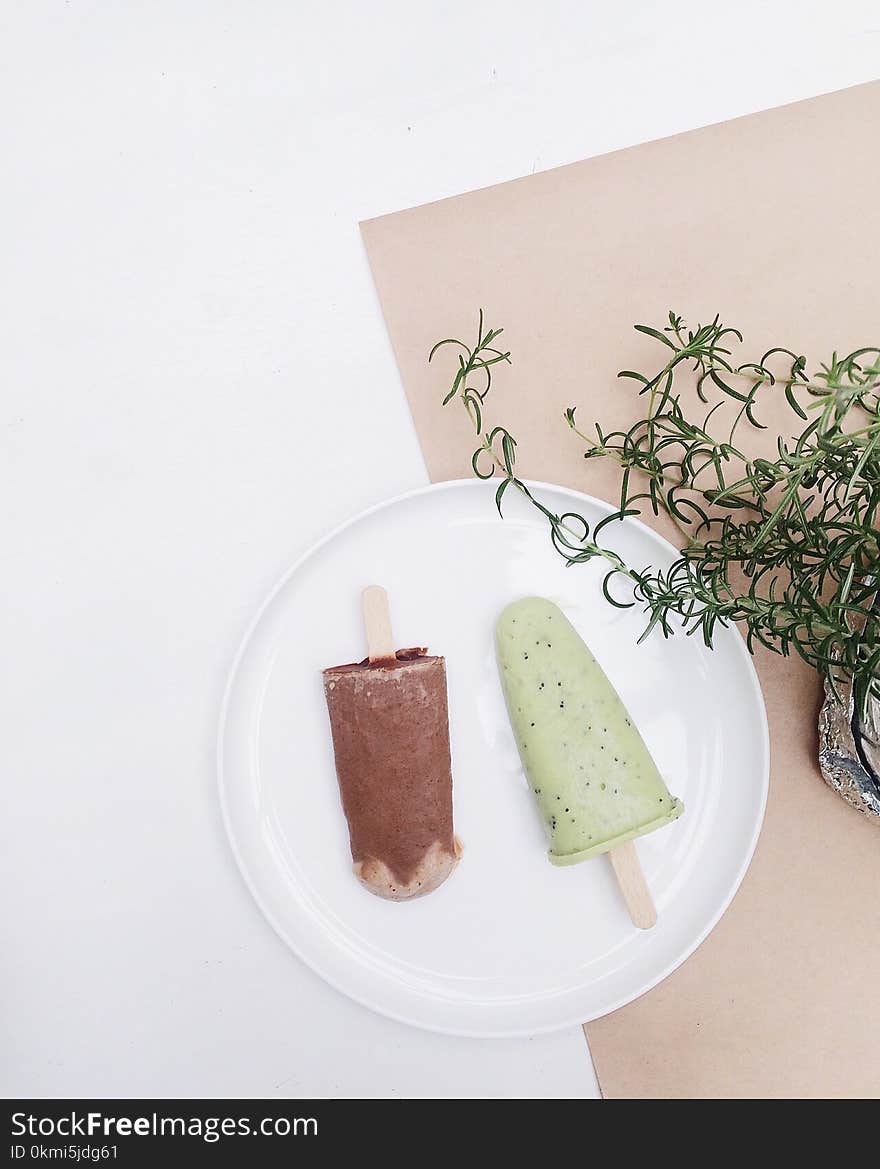 Two Assorted-flavor Ice Pop on Top of White Plate