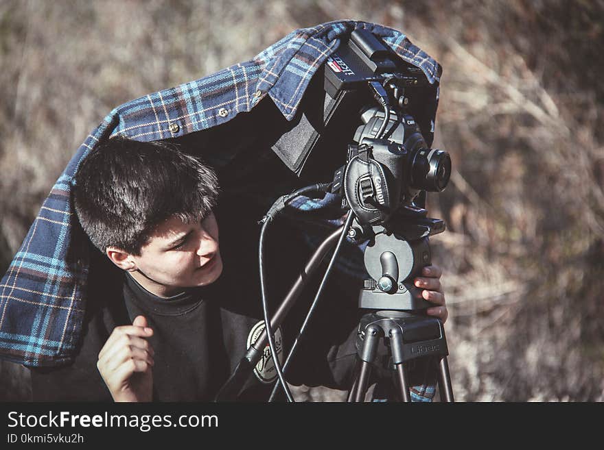 Photo of Man Setting Up Dslr Camera on Tripod