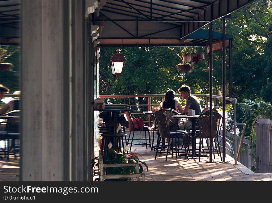 Man and Woman Sitting on Chair Near Hand Railings