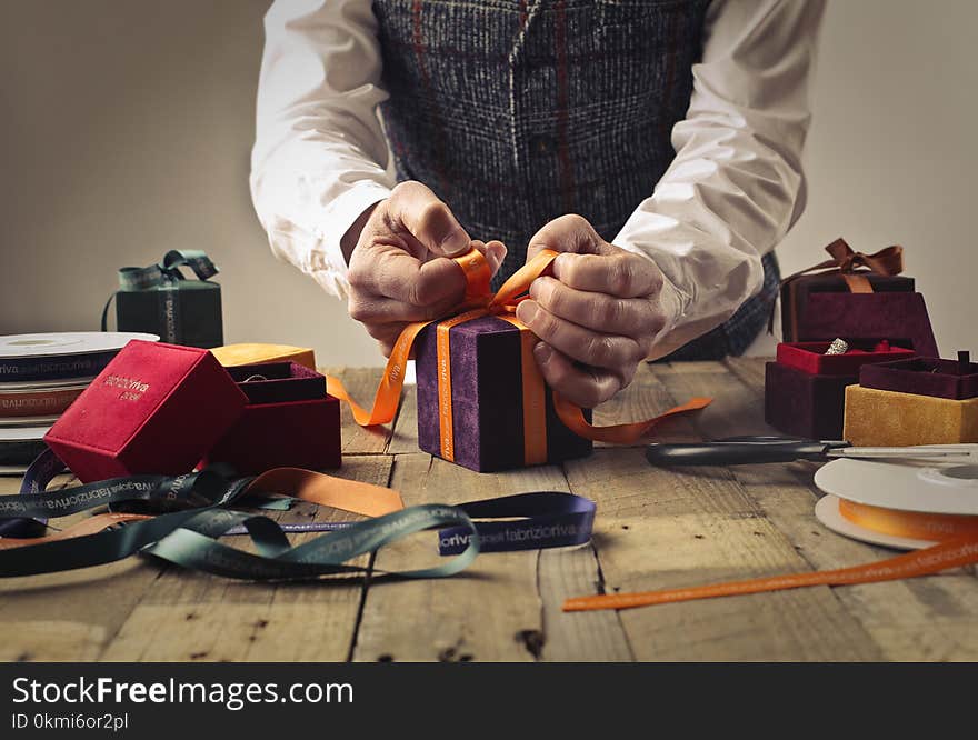 Person Tying Ribbon on Purple Gift Box