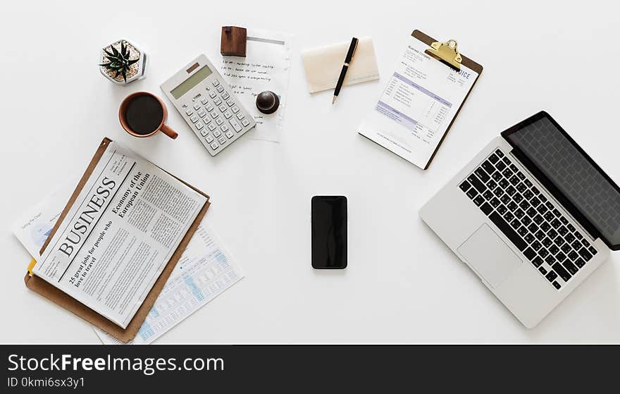 White Calculator Beside Brown Ceramic Mug