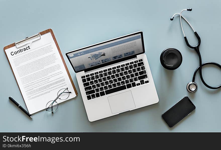 Macbook Pro Near Stethoscope and Paper Clipboard